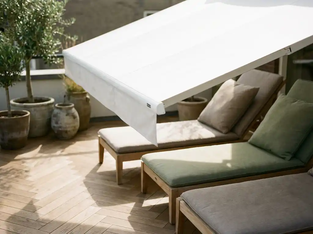 Wit gemotoriseerd zonnescherm boven Nederlands terras met visgraat eiken vloer en linnen kussens in salie en taupe